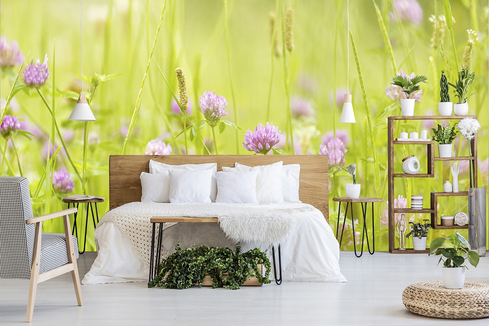 Fototapete - Schlafzimmer mit grüner Wiesen-Fototapete und lila Blumen im Hintergrund, ergänzt durch moderne Holzmöbel und helle Einrichtung