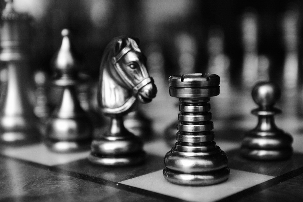 Papier peint photo - Détail d'un échiquier avec des pièces d'échecs, dont un cavalier et une tour, en noir et blanc