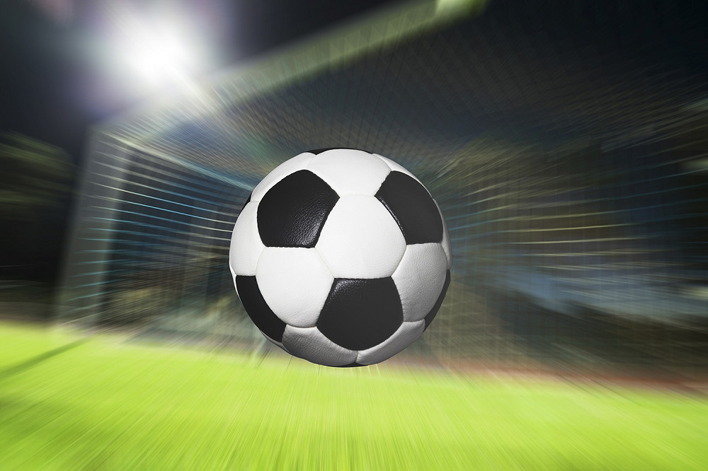 Wall mural - Football flying at speed towards a goal, background blurred