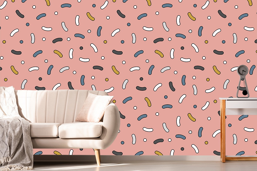 Papier peint photo - salon avec un papier peint rose et un motif ludique, à côté un canapé crème et une table
