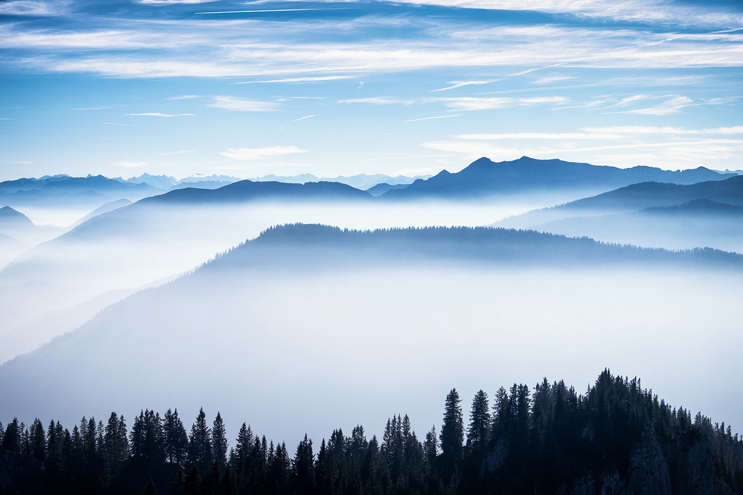 Fototapete - Nebelige Berglandschaft mit Wald und klarem Himmel in der Ferne