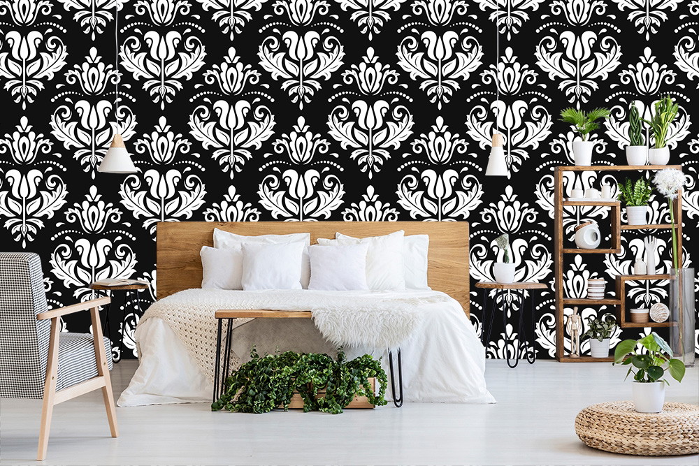 Fotobehang - Woonkamer met een zwart-wit barokpatroon als achtergrond, een houten bed en planten