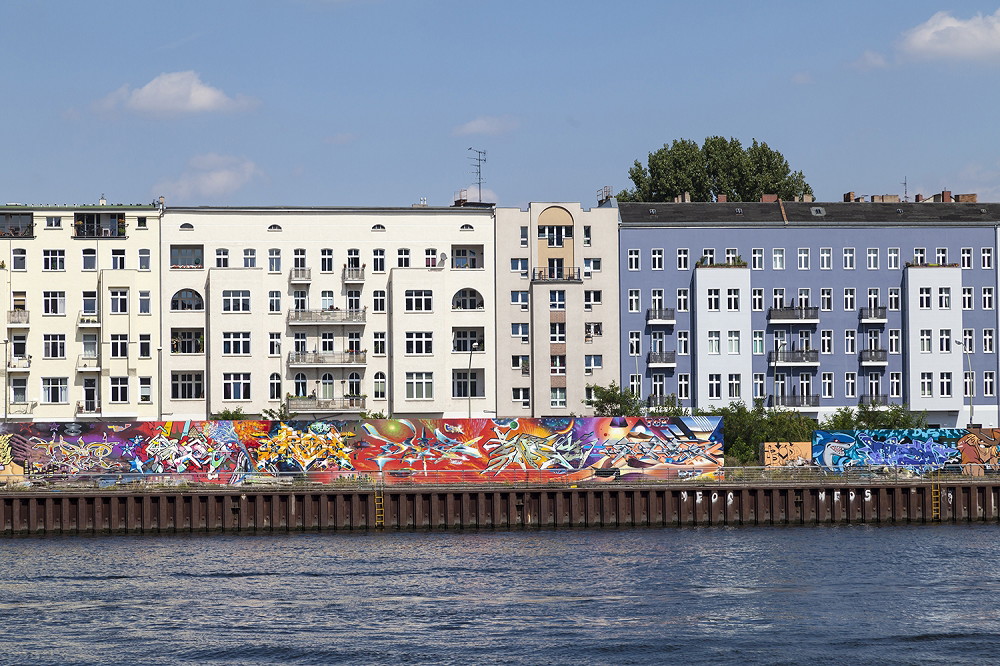 Fototapeta - Ściana z kolorowym graffiti na budynku obok brzegu rzeki