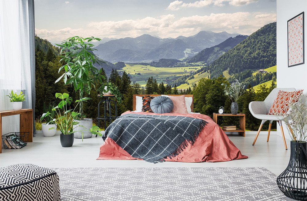 Papier peint photo - chambre avec un lit, des plantes et un papier peint représentant un paysage de montagne pittoresque