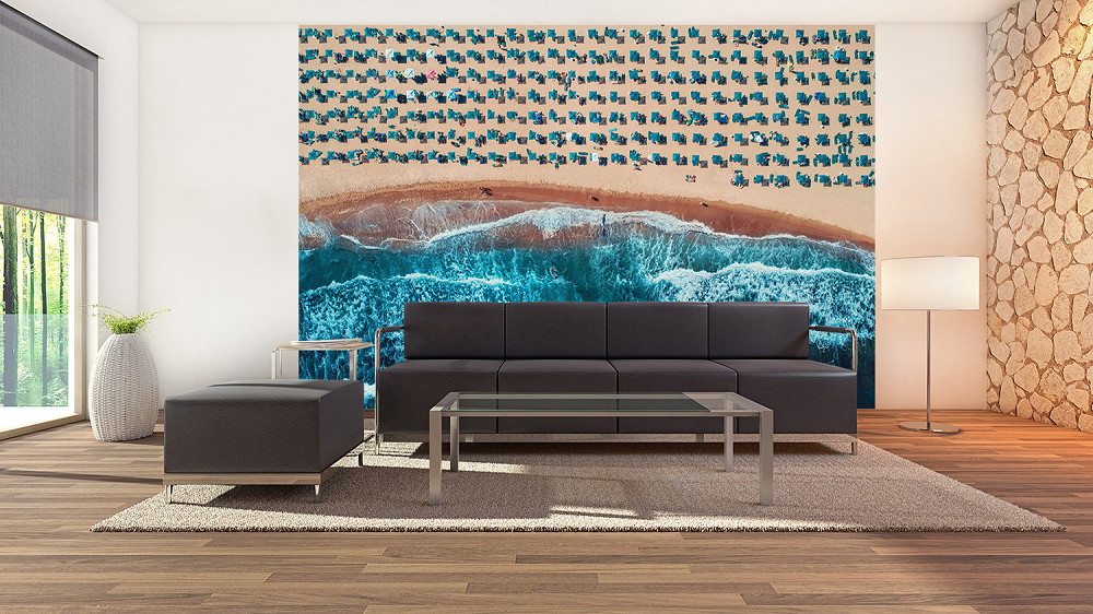 Fototapete - Luftaufnahme eines Strandes mit türkisfarbenem Meer, Wellen und Liegestühlen in einem modernen Wohnzimmer
