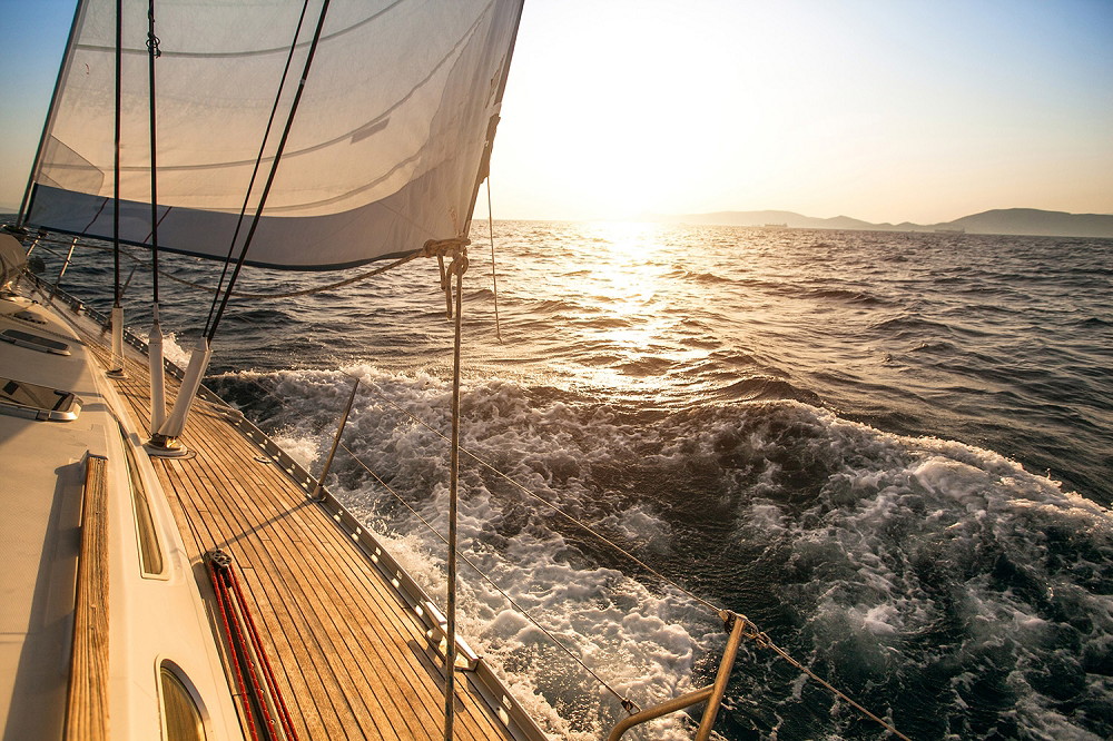 Fotobehang - Uitzicht vanaf een zeilboot op de zee tijdens een zonsondergang