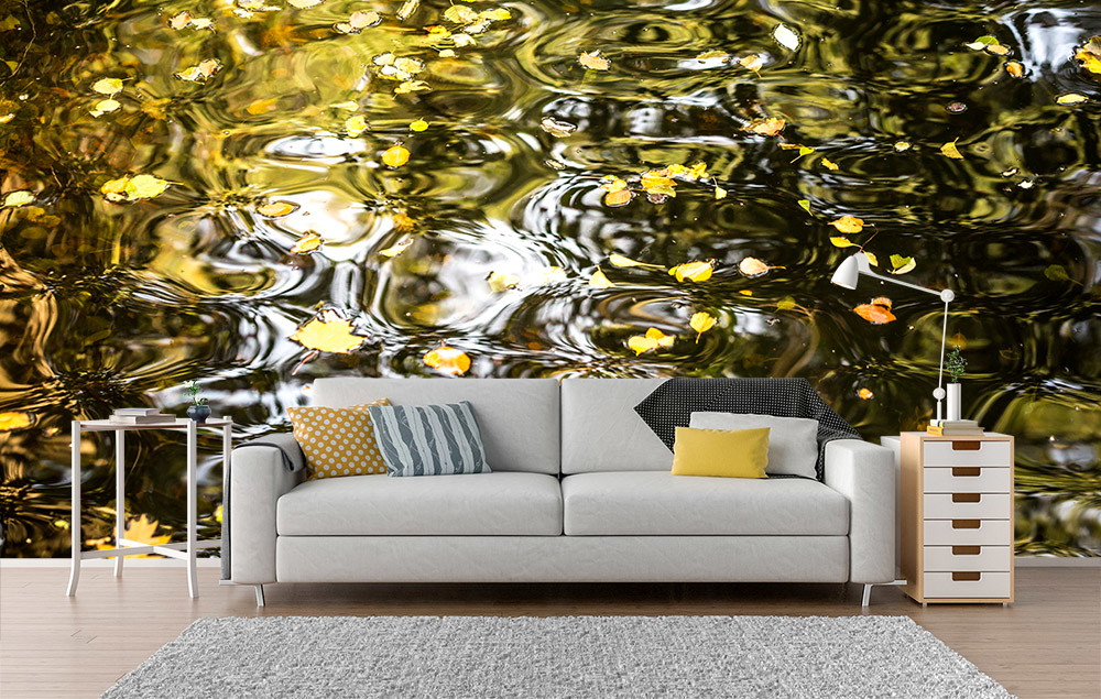 Wall mural - scene of a living room with a sofa in front of a wall mural of a river of water with yellow leaves
