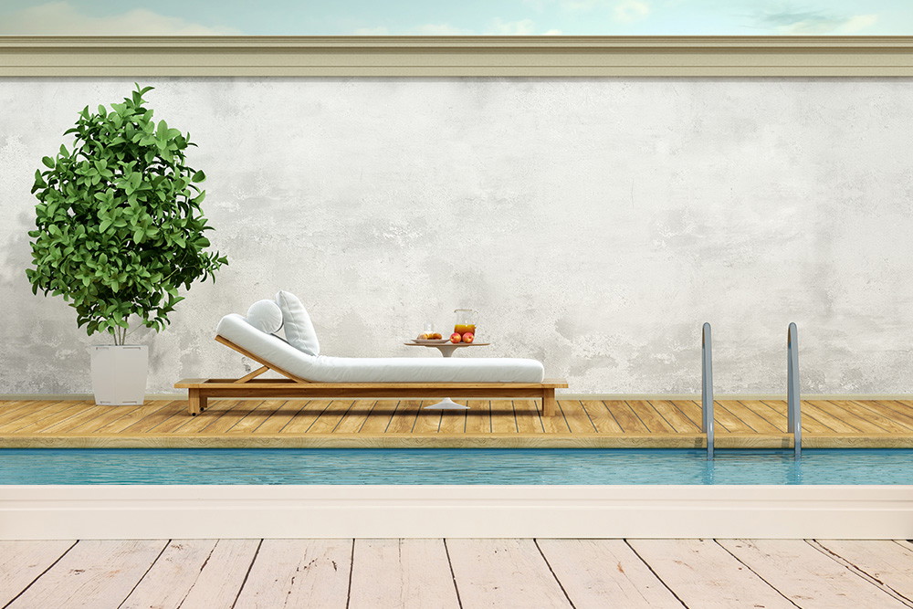 Fototapete - Liegestuhl und Pflanze am Pool auf Holzdielen mit heller Betonwand im Hintergrund