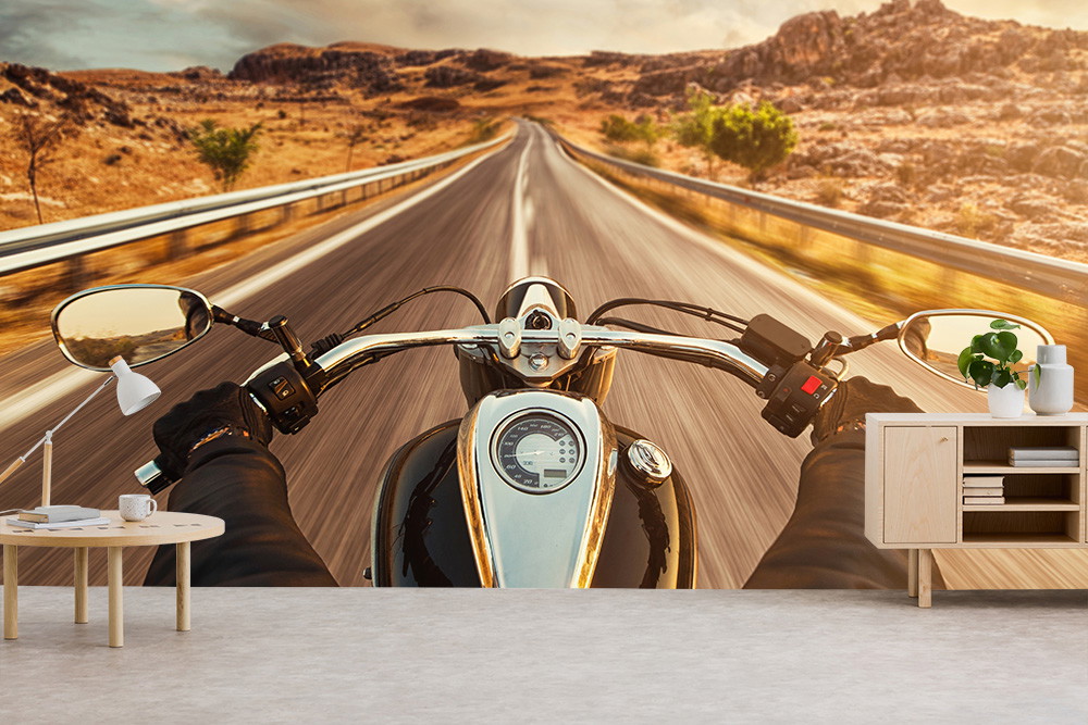Fototapete - Perspektive eines Motorradfahrers auf einer leeren Landstraße, umgeben von trockener Landschaft und unter einem goldenen Himmel