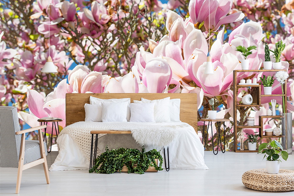 Fotobehang - Moderne slaapkamer met bed en een muur met roze magnoliabloemen