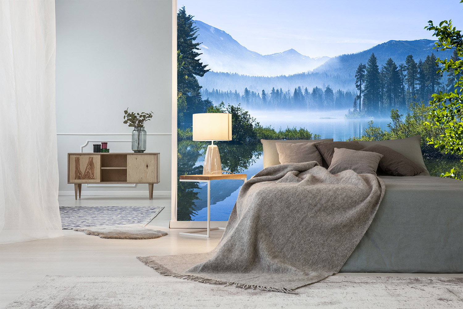 Fotobehang - Slaapkamer met een sfeervolle afbeelding van een rustig meerlandschap, bergen op de achtergrond en zonlicht dat door de bomen schijnt