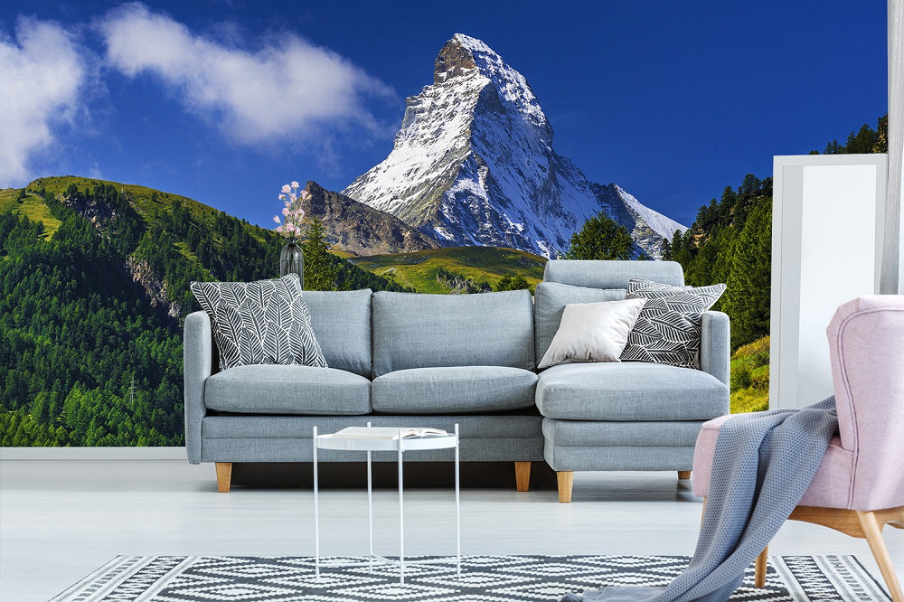 Fototapete - Wohnzimmer mit Sofaecke vor einer Fototapete des Matterhorns und grüner Landschaft
