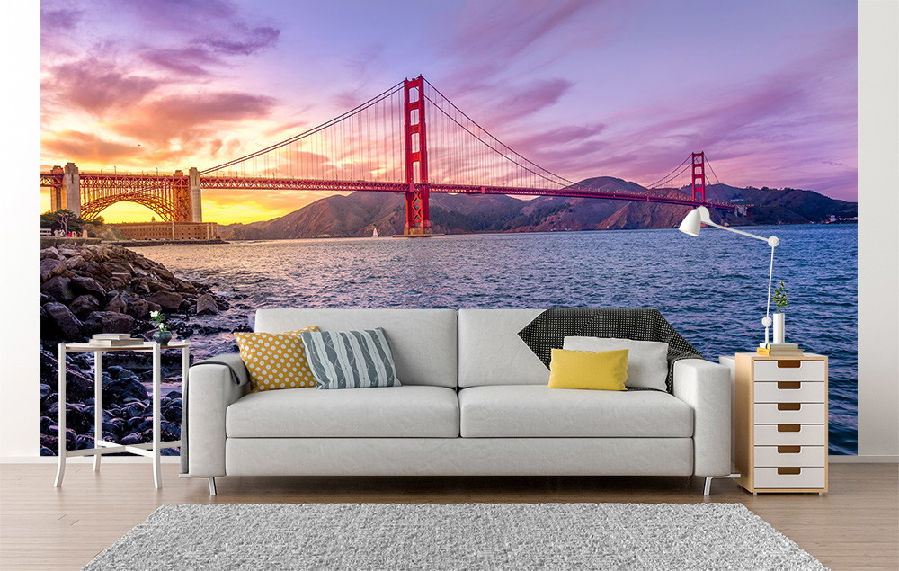 Papier peint photo - Salon avec le spectaculaire papier peint photo du Golden Gate Bridge au coucher du soleil, canapé au premier plan