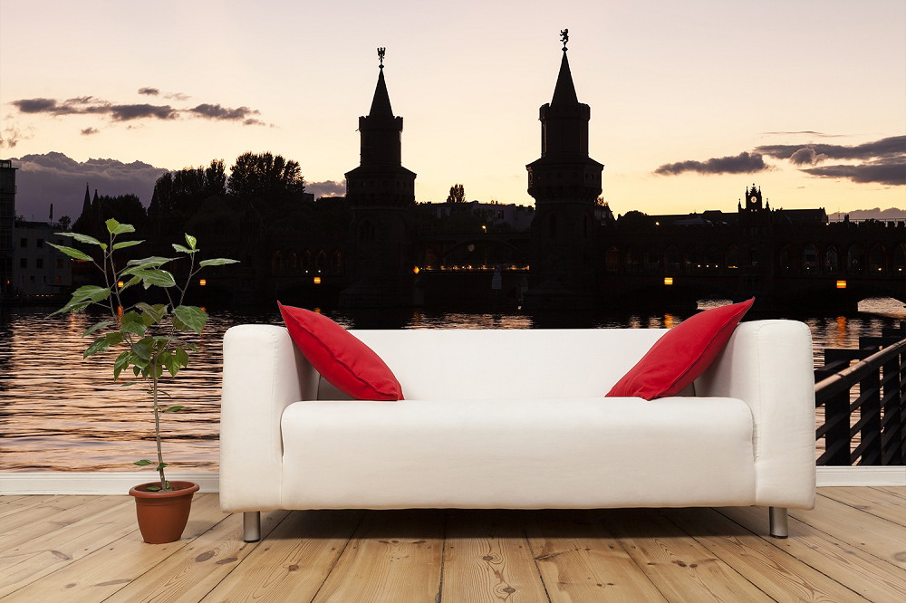Fototapete - Berliner Brückenpanorama bei Sonnenuntergang im Hintergrund eines Sofas mit roten Kissen