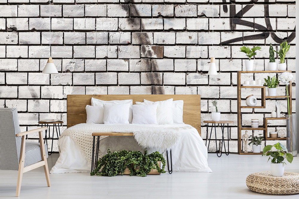 Fototapete - Schlafzimmer mit graffitiverzierter Ziegelwand, Holzregal, Pflanzen und skandinavischen Möbeln
