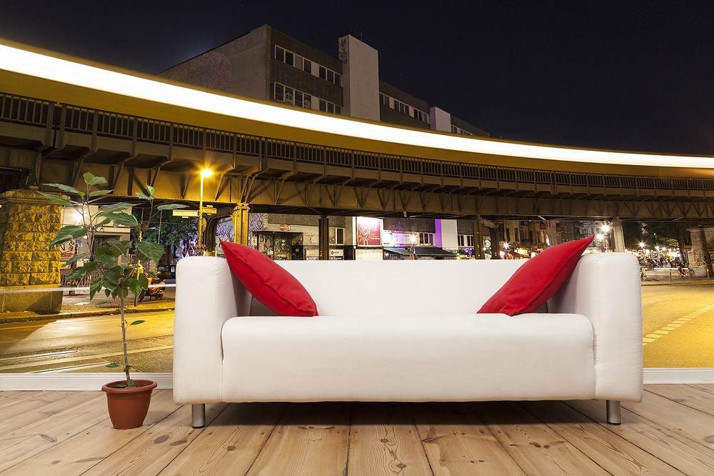 Fototapeta - Biała sofa z czerwonymi poduszkami przed nocnym krajobrazem miasta z przejeżdżającym pociągiem i sceną miejską w tle