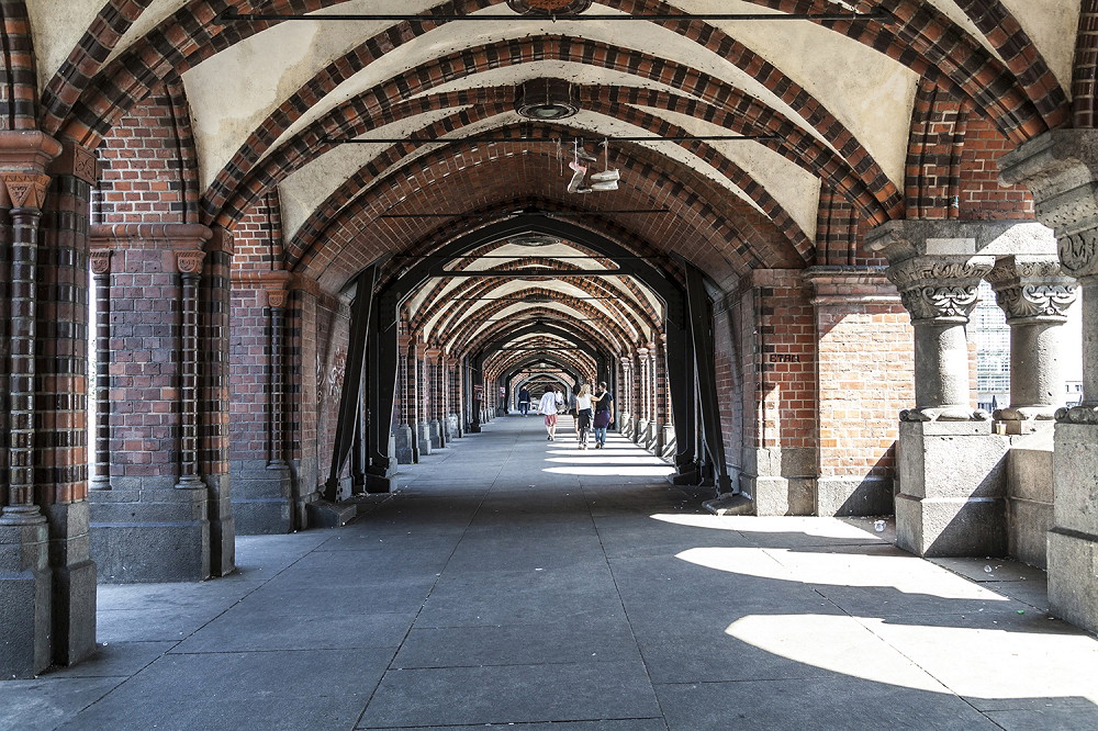 Wall mural - Interior view of a historic brick bridge with arched passageway and pedestrians in daylight