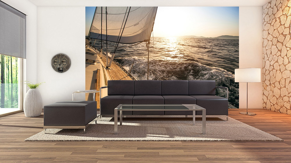 Wall mural - Stylish living room with a wall mural of a sailing boat at sunset on the sea