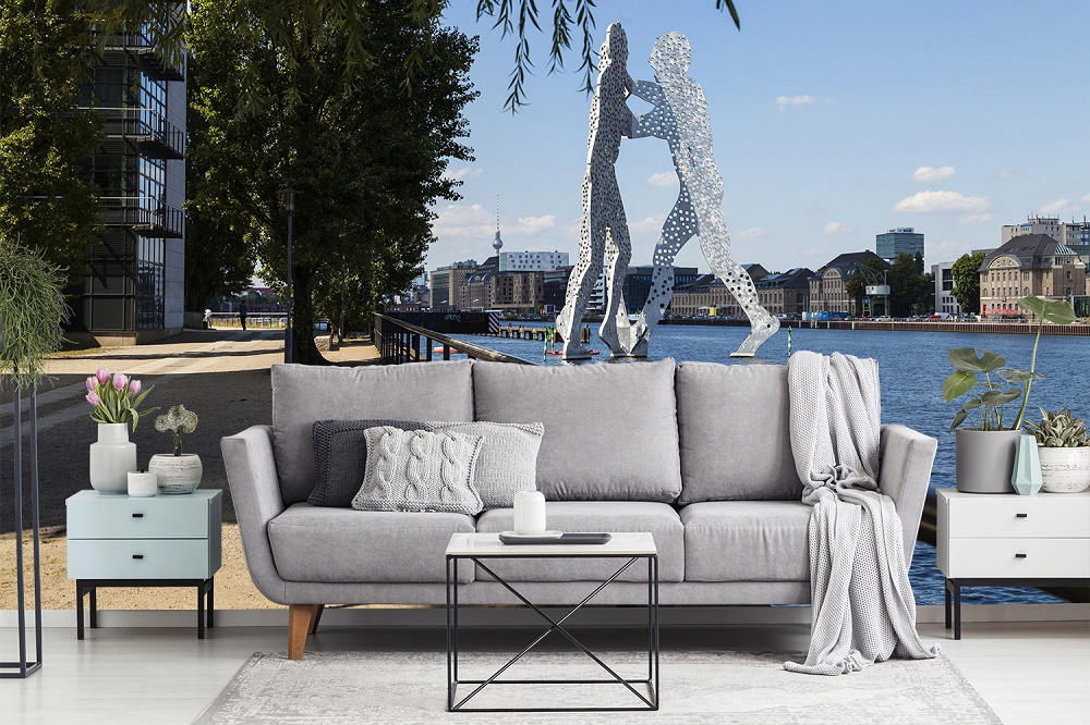 Muurschildering - Woonkamer met grijze bank voor uitzicht op de stad Berlijn en Molecule Man sculptuur bij de rivier