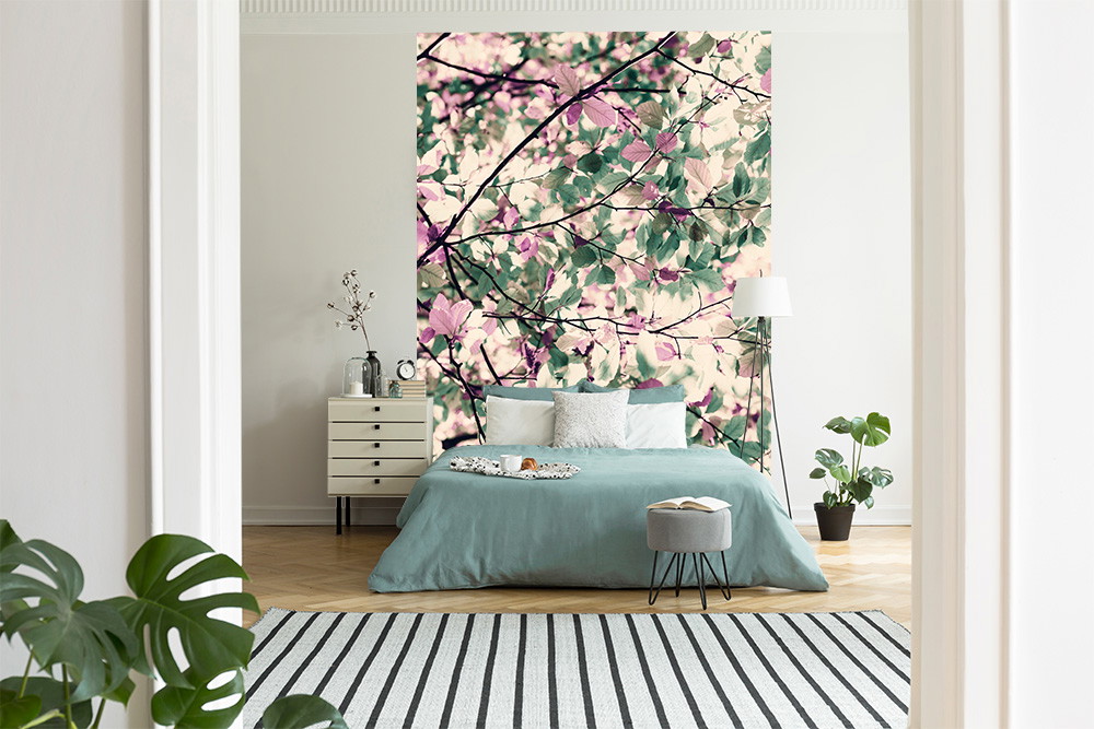 Fotomurale - Camera da letto luminosa con parete a motivi floreali, piante e arredamento moderno.