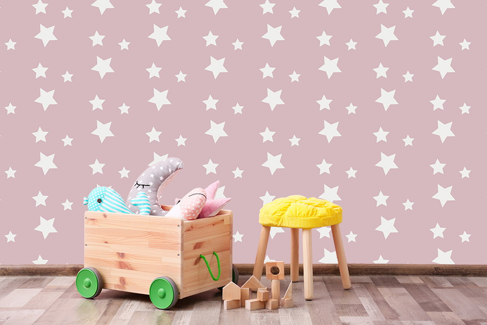 Papier peint photo - mur rose avec étoiles blanches, tabouret jaune et coffre à jouets dans la chambre d'enfant