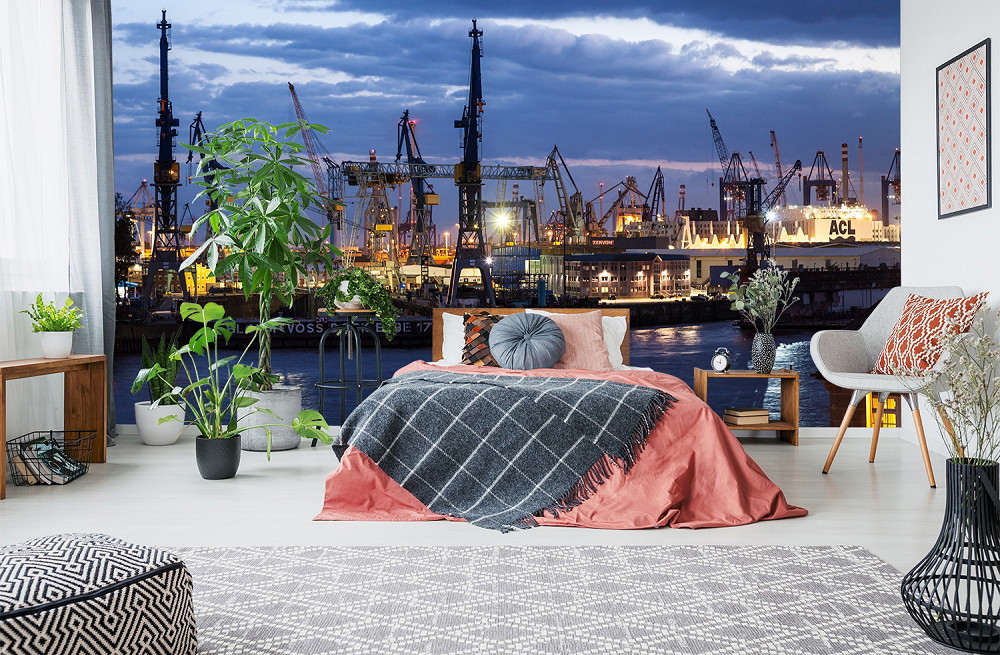 Fototapete - Schlafzimmer mit großen Pflanzen und Blick auf einen beleuchteten Hafen bei Nacht