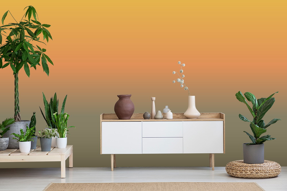 Wall mural - Living room with green plants and a white-brown sideboard against a yellow-orange gradient background