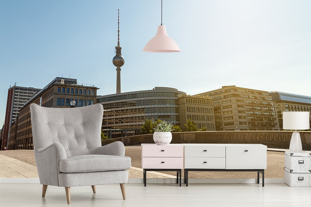 Wall mural - Bright room with cosy armchair and chest of drawers, the view shows a Berlin cityscape with television tower