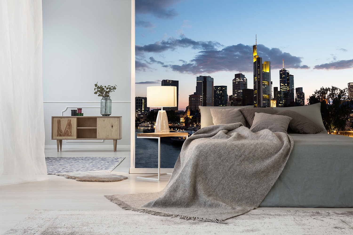 Fototapete - Schlafzimmer mit großer Fototapete der Frankfurter Skyline, einem modernen Holztisch mit Lampe und einer einladenden Bettdecke