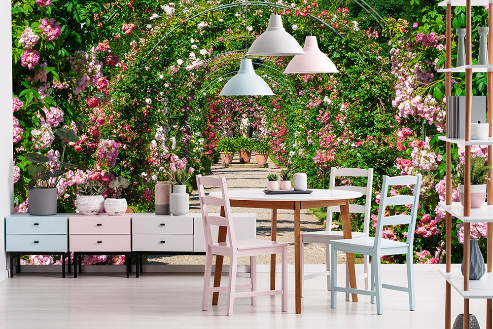 Fototapete - Esszimmer mit Tisch und Stühlen vor einer Wand mit Rosenbogen und blühendem Garten