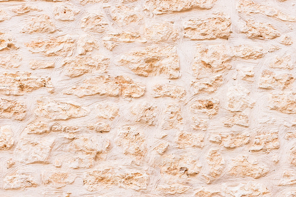 Wall mural - Close-up of a textured stone wall in beige and white tones, reminiscent of historic buildings