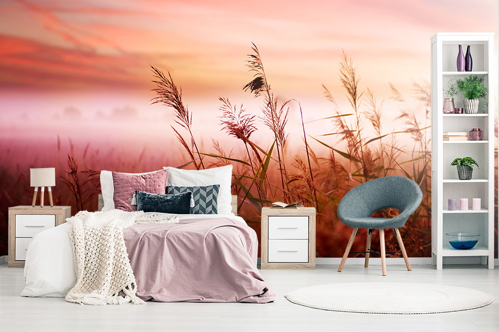 Wall mural - Bedroom with pastel-coloured bed linen and a wall mural with a sunrise over a field of grass