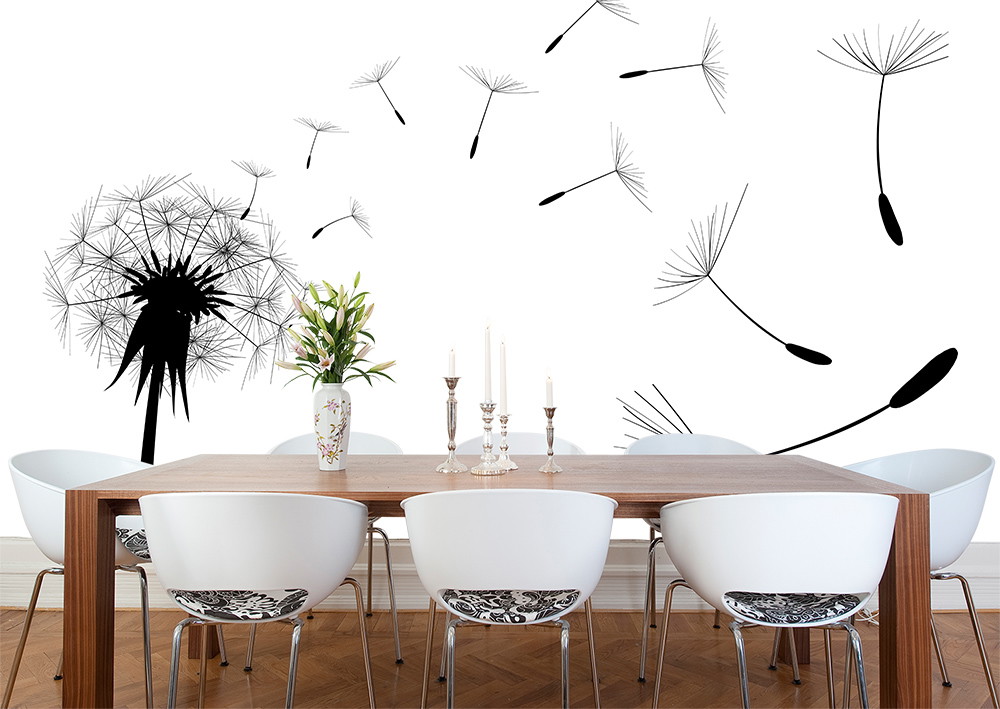 Wall mural - Black and white dandelion flower with floating seeds on a wall behind a dining table with white chairs