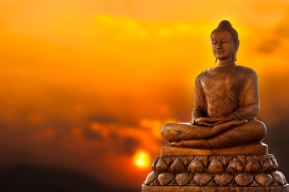 Fototapete - Meditierende Buddha-Statue mit warmem, orangefarbenem Sonnenuntergang im Hintergrund