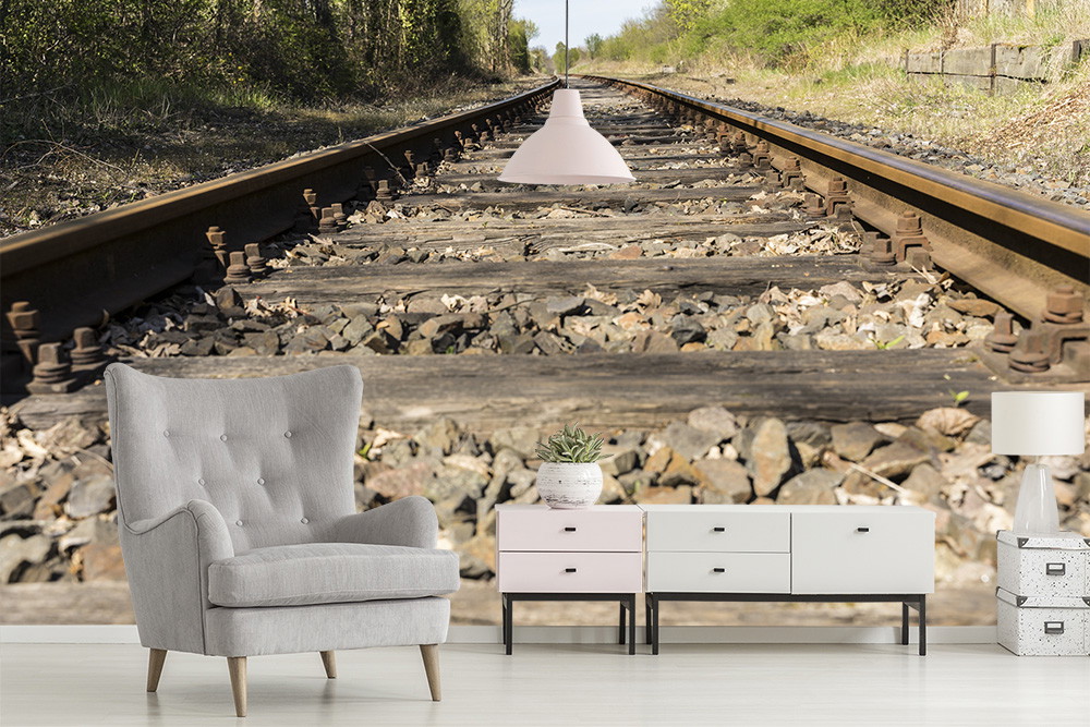 Papier peint photo - des rails de chemin de fer traversent un paysage verdoyant, combiné à une décoration intérieure moderne.