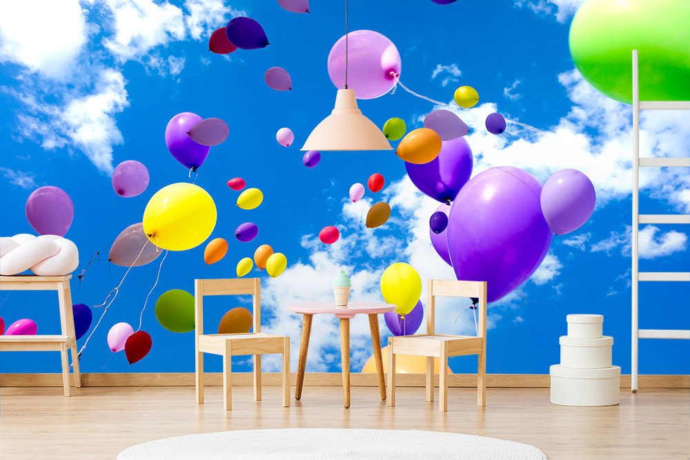 Wall mural - Colourful balloons floating in the blue sky with clouds, surrounded by wooden furniture in the children's room