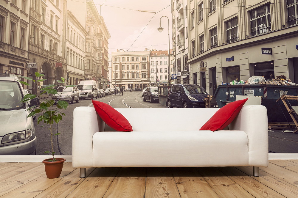 Wall mural - Living room with white sofa and red cushion in front of a wallpaper with city street motif and historic buildings