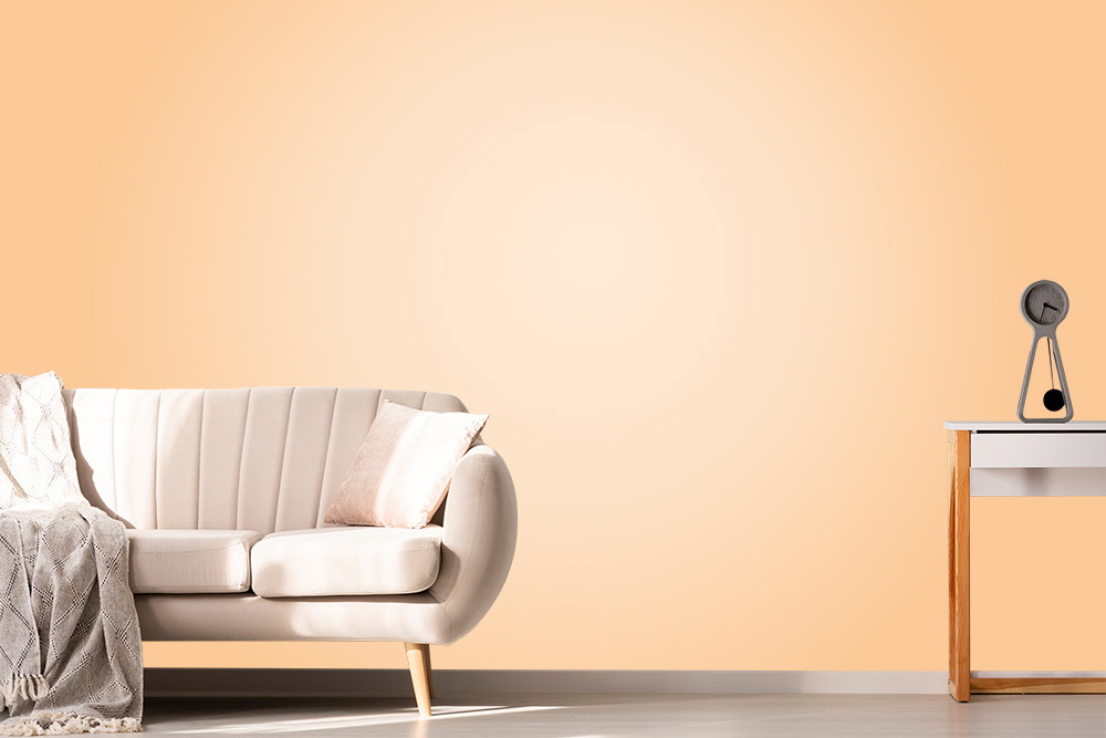 Fototapete - Helles Wohnzimmer mit cremefarbenem Sofa, beiger Decke und modernem Beistelltisch mit stilvoller Lampe vor einer sanft orangefarbenen Wand