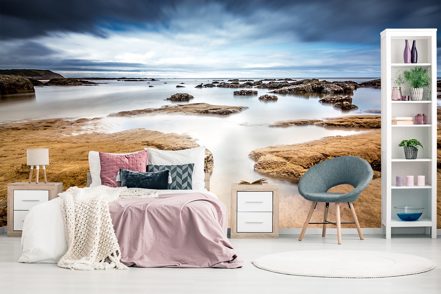 Photomural - Bedroom with bed and blue chair, on the wall photomural with coastal landscape at sunset