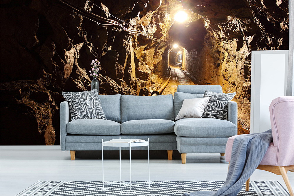 Fototapete - Wohnzimmer mit grauem Sofa und stimmungsvoller Höhlenlandschaft an der Wand