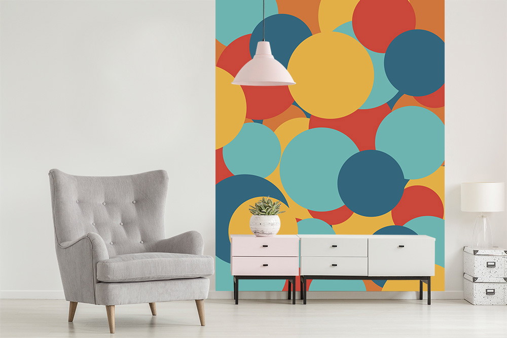 Fotobehang - Woonkamer met grijze fauteuil en kleurrijk behang met grote cirkels in blauw, geel en rood