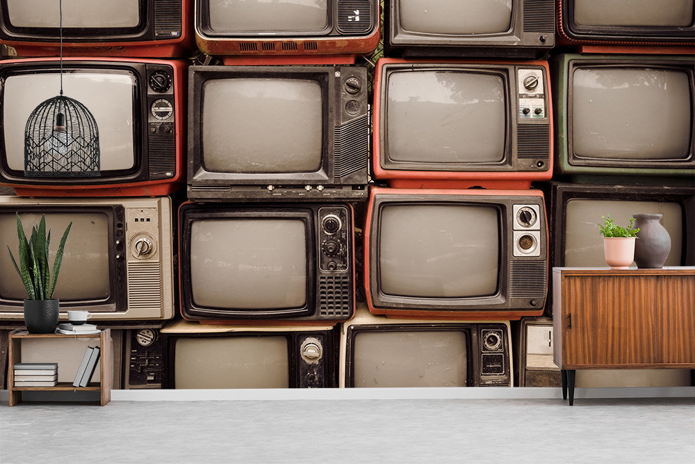 Fototapete - Gestapelte alte Fernseher in verschiedenen Vintage-Designs für ein nostalgisches Ambiente