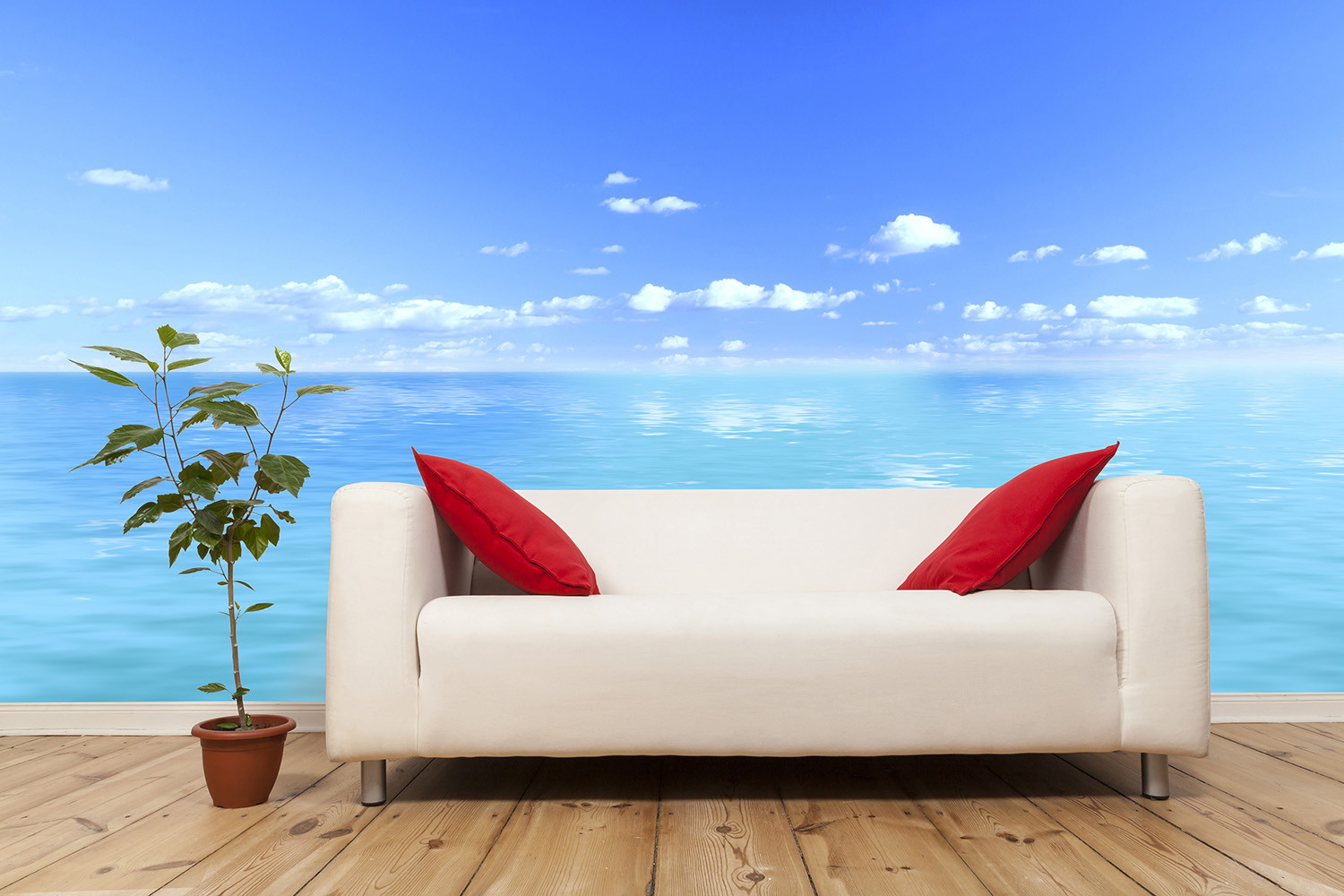 Fotobehang - Witte bank met rode kussens tegen een achtergrond met uitzicht op zee en een blauwe lucht, met daarnaast een kleine bloempot
