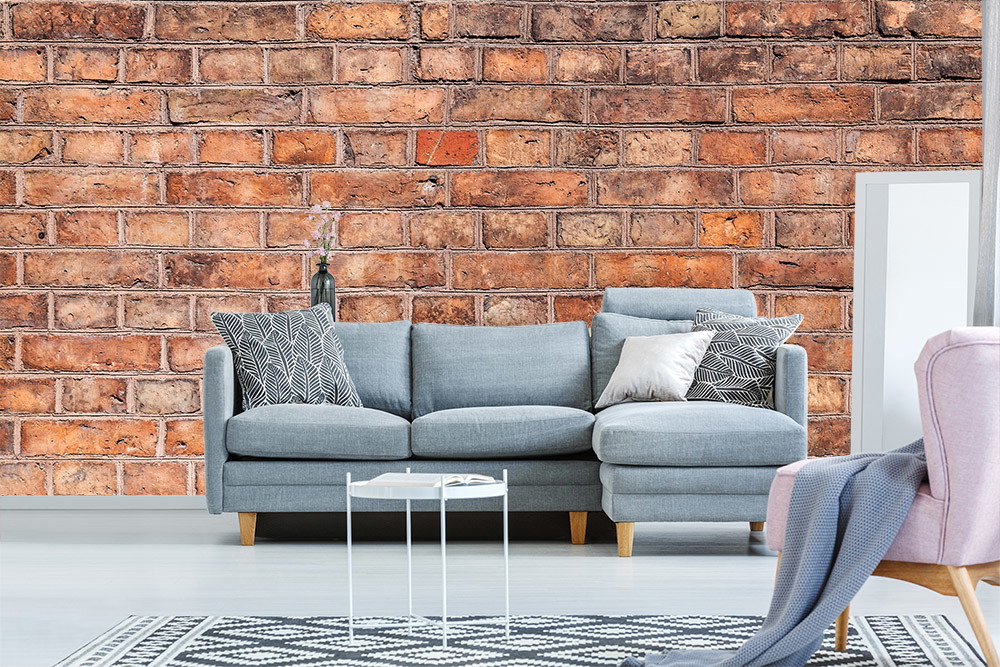 Fototapete - Wohnzimmer mit einer gemütlichen Sitzgruppe vor einer Wand mit Ziegelstein-Design