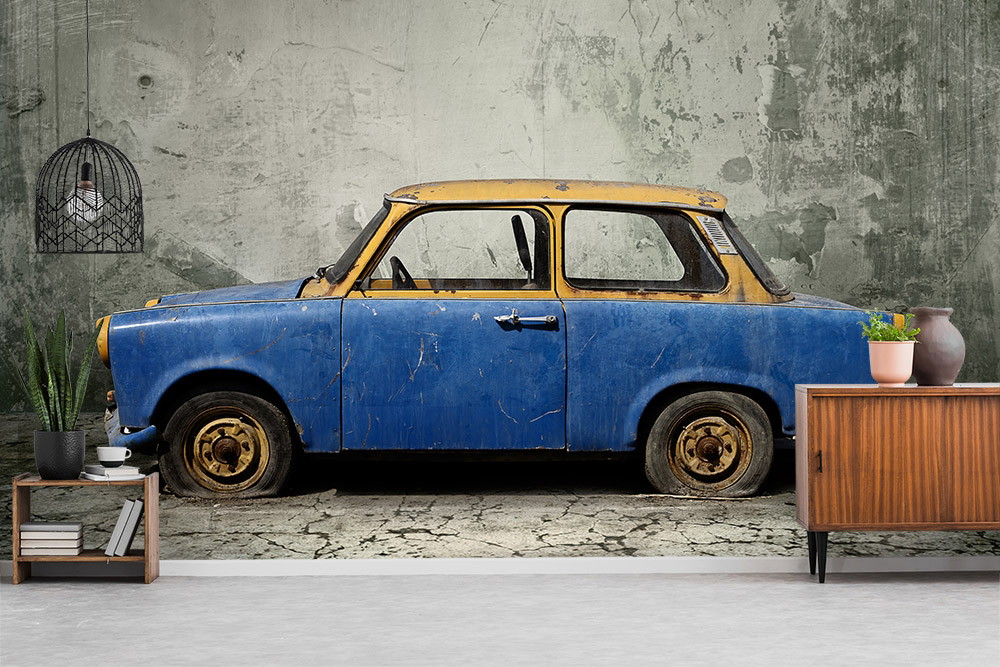 Wall mural - Rusty blue vintage-style car parked in front of an old, grey concrete wall in a modern space.