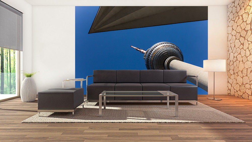Fototapete - Innenraum mit grauem Sofa und Bild eines modernen Turms gegen blauen Himmel