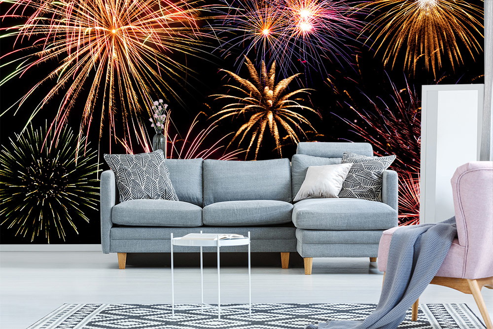 Wall mural - Colourful fireworks behind a modern grey couch in the living room