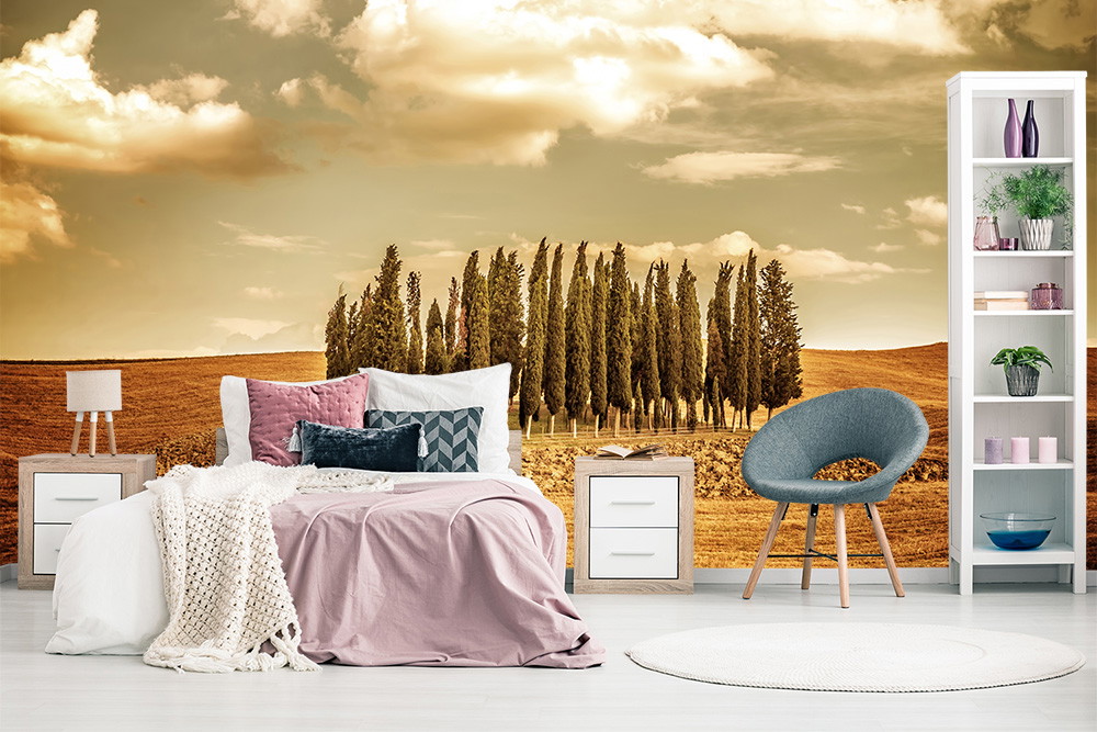Fototapete - Schlafzimmer mit Landschaftshintergrund von Zypressen und goldenem Feld, begleitet von Möbeln in natürlichen Tönen.
