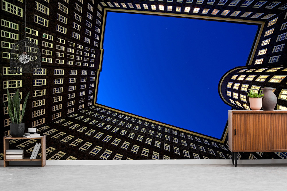 Fototapete - Blick nach oben zwischen hohen Gebäudewänden, die den klaren, blauen Himmel einrahmen.
