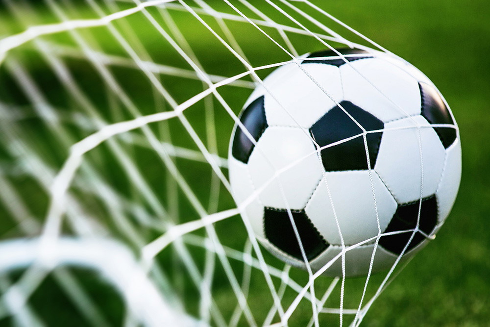 Muurschildering - Een voetbal vast in een doelnet op een groen veld